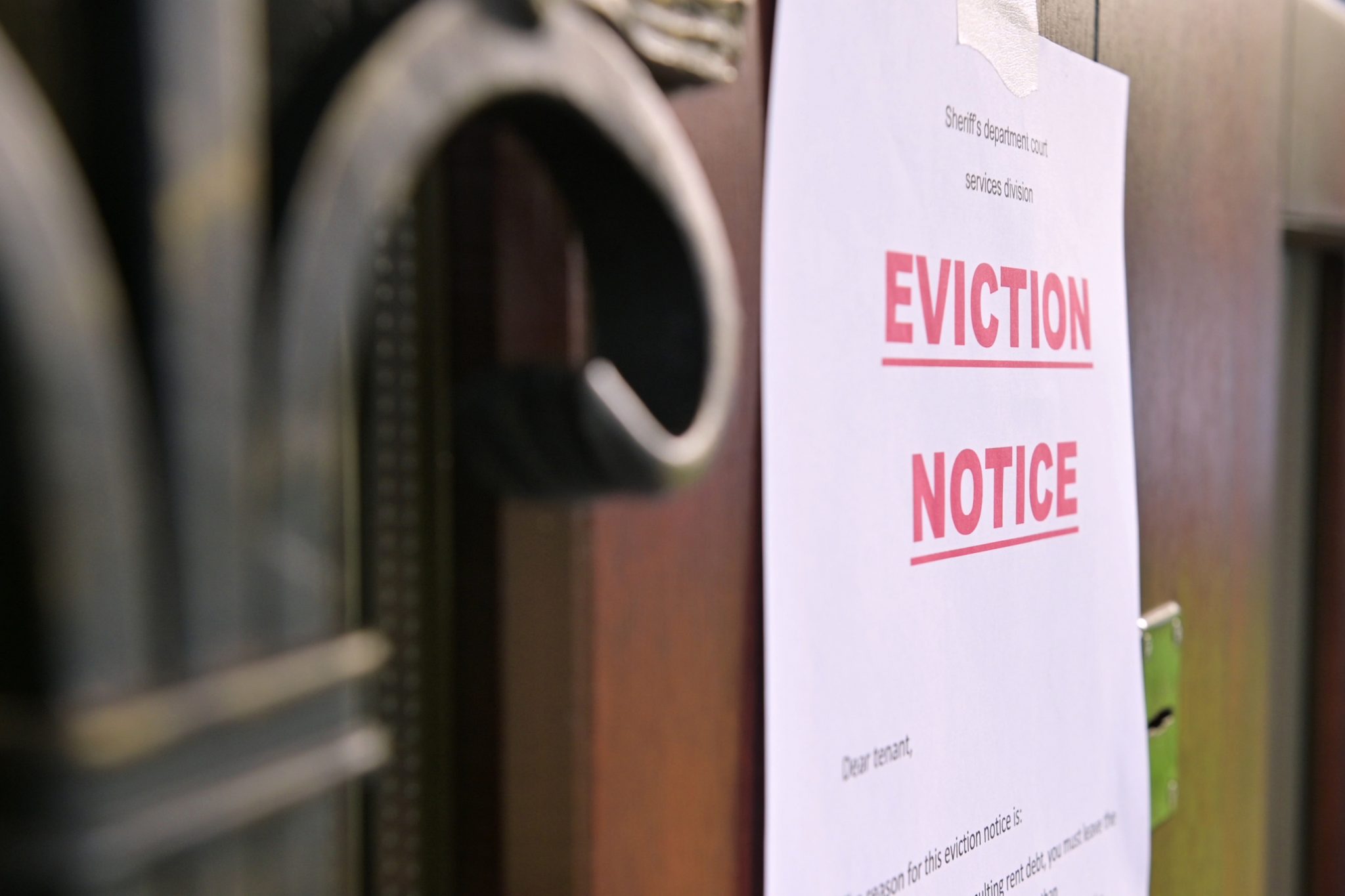 A notice of eviction of tenants hangs on the door of the house, front view.