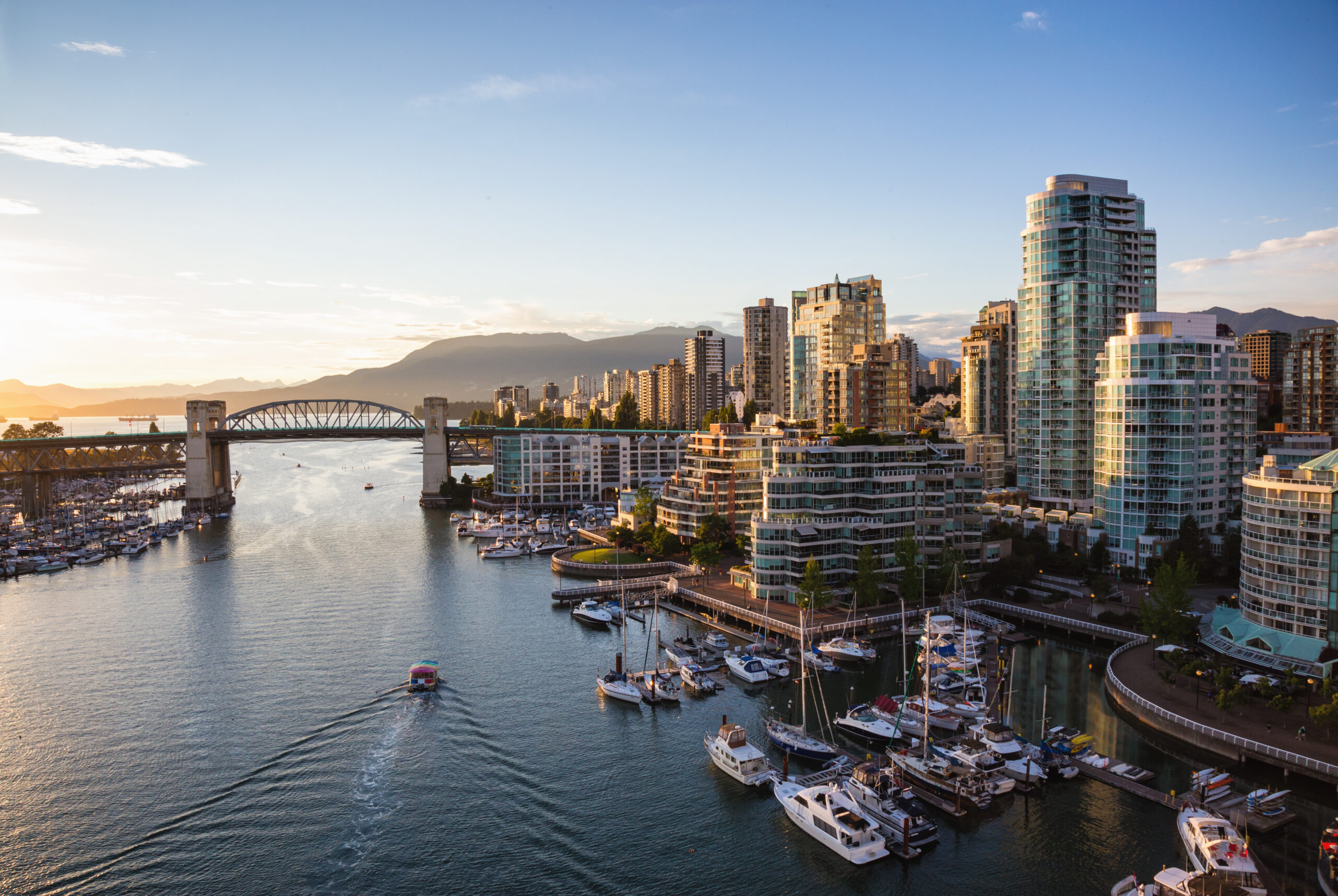 View of Downtown Vancouver and Burrard Bridge at False Creek during sunny sunset.